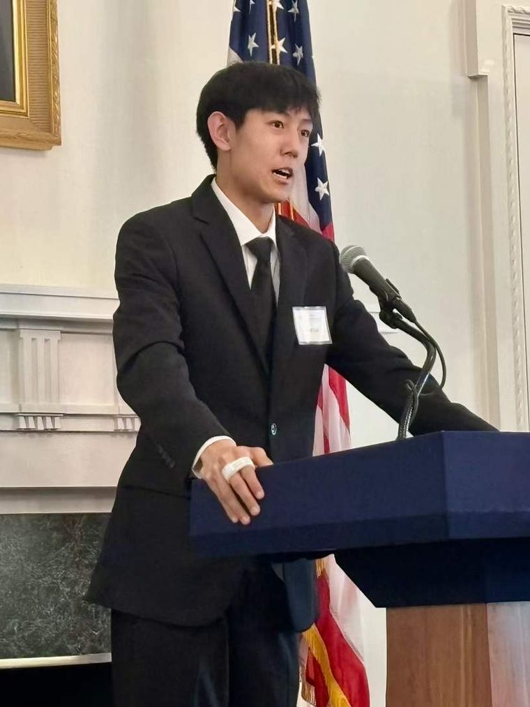 一位男生在正式场合的讲台上发言