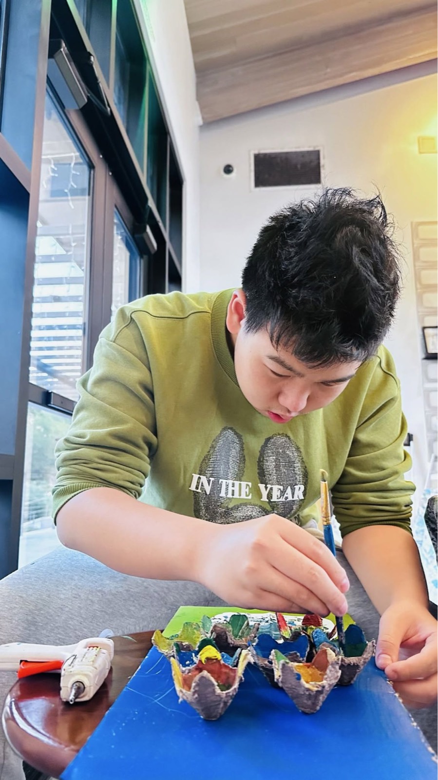 社员为蛋托上色，蛋盒里调着彩色颜料
