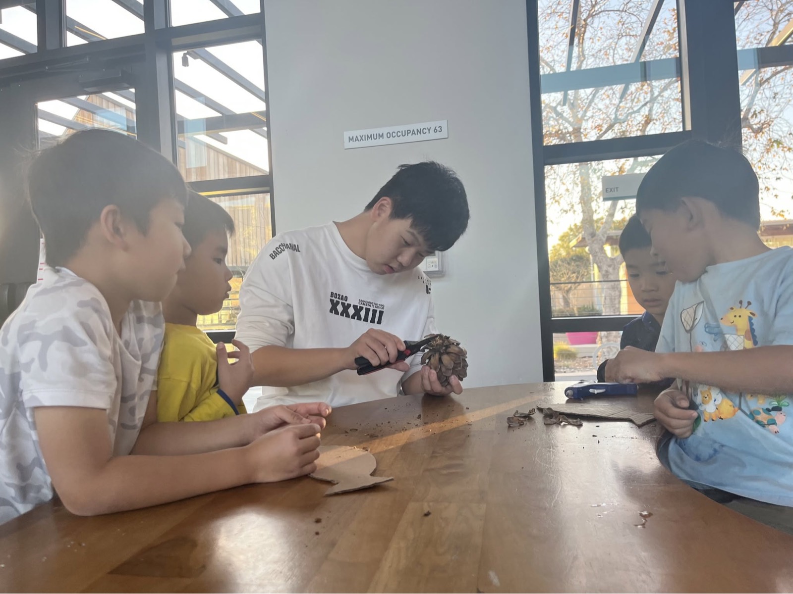 工作坊上向几名孩子示范松果的处理方法