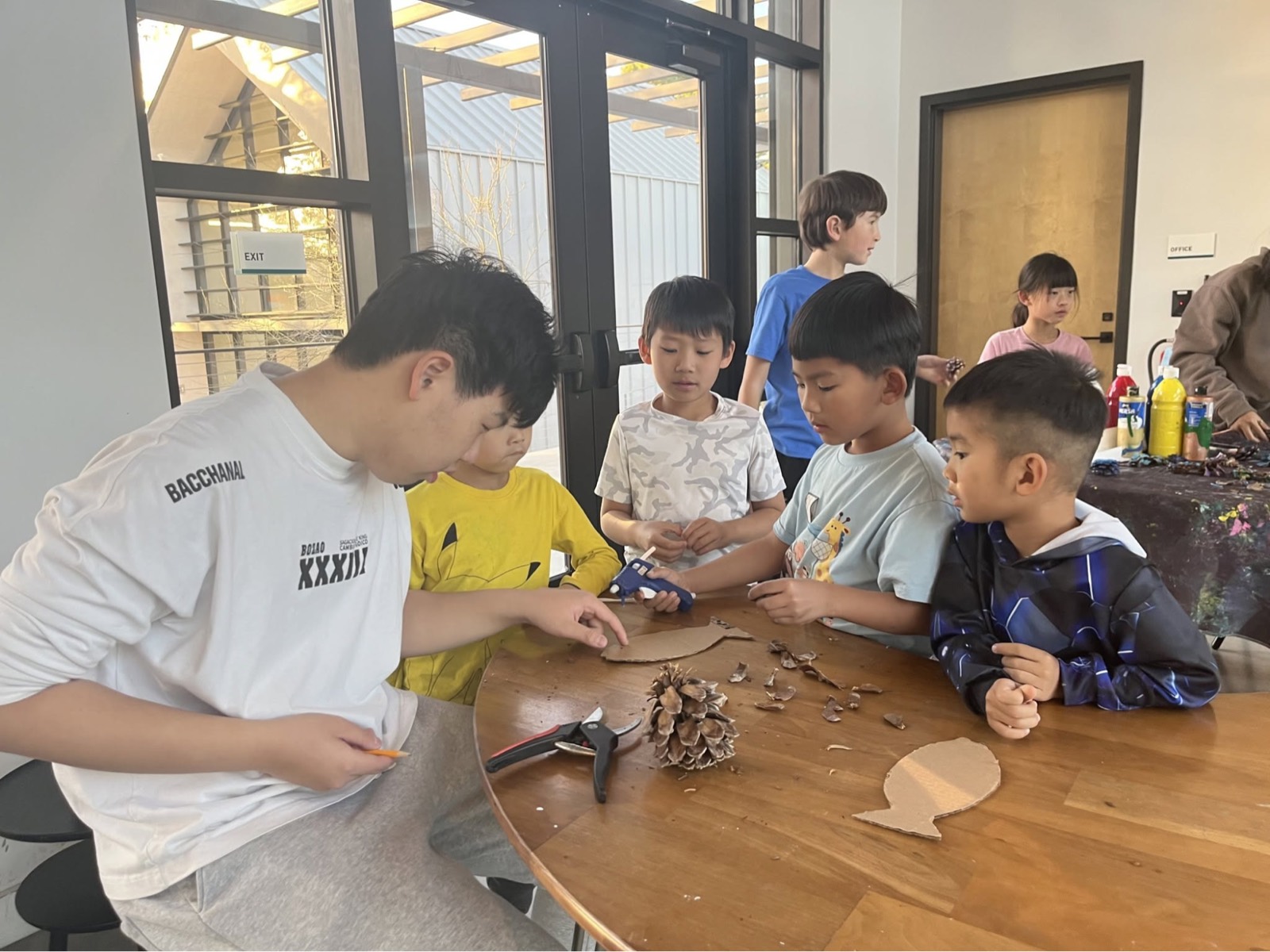 孩子们围着桌子处理松果与自然材料