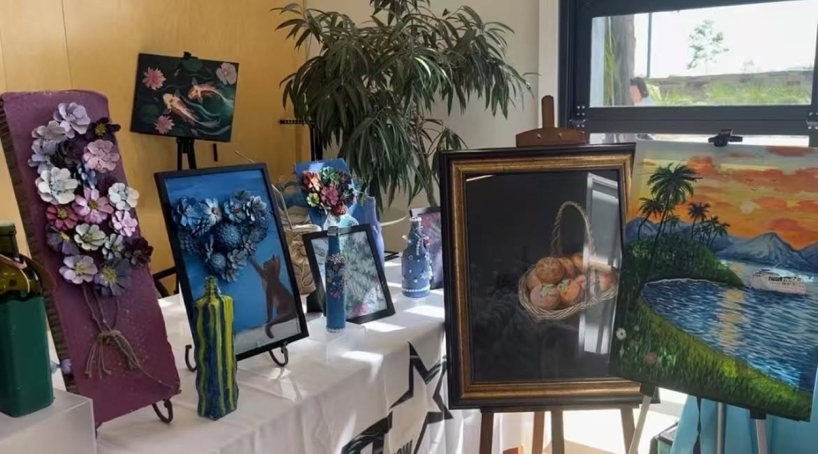 社区展台，装裱画作与彩绘瓶罐并排陈列